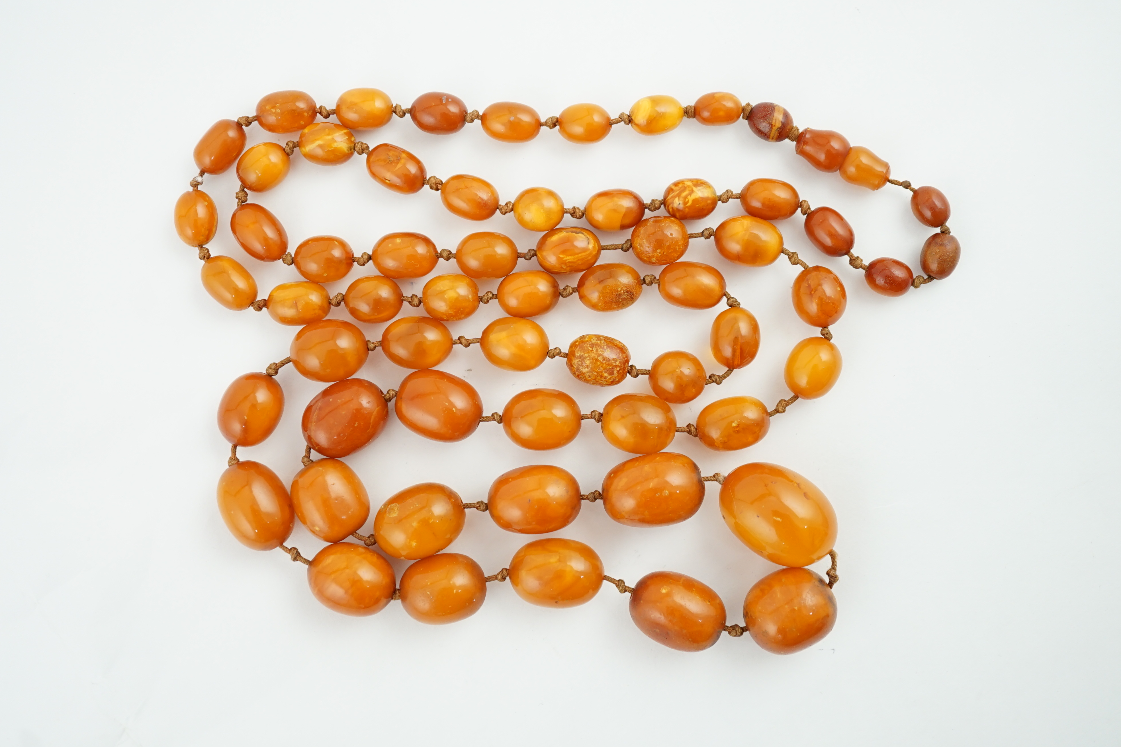 A long single strand graduated amber bead necklace